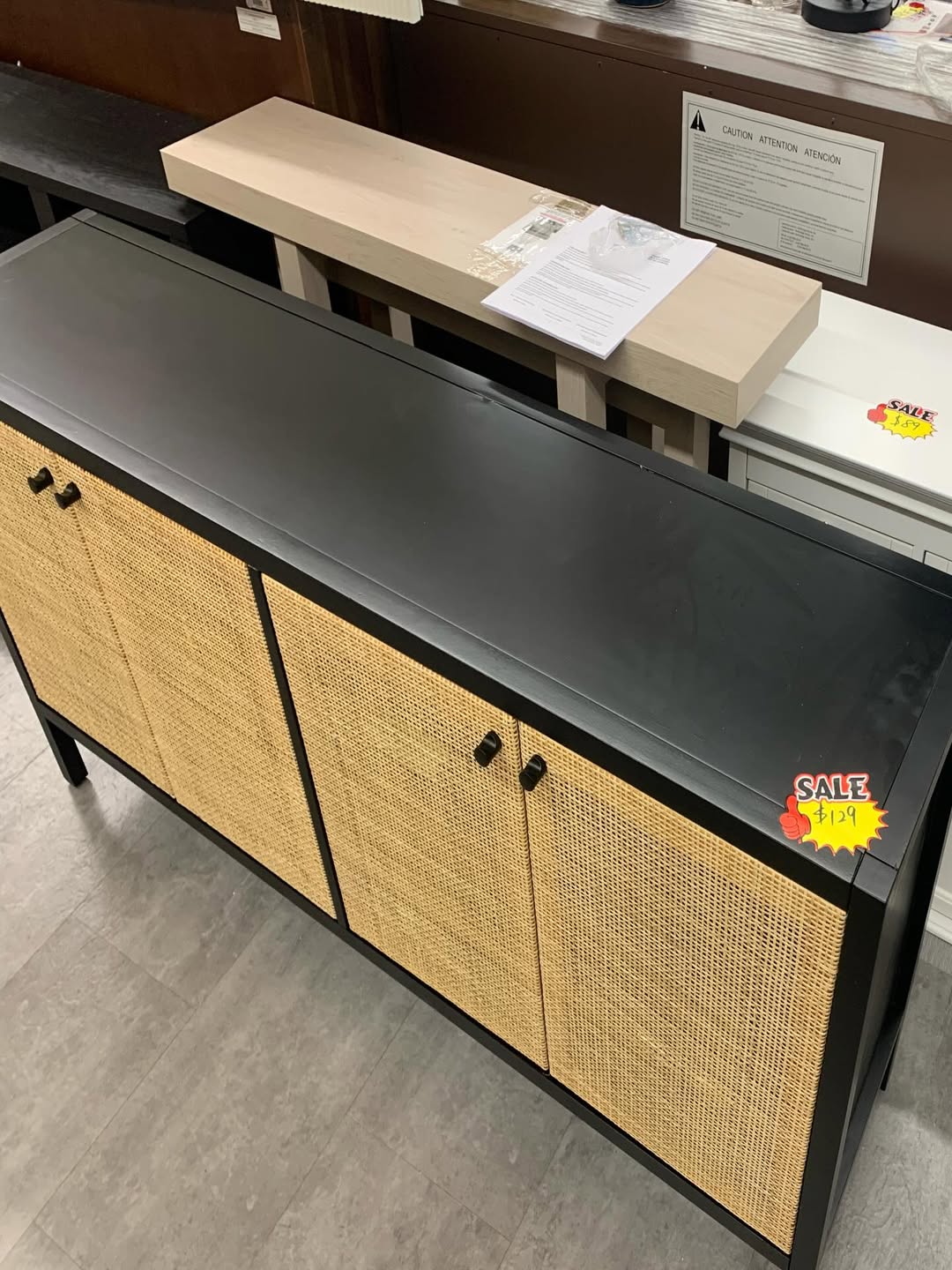 Black storage sideboard cabinet with natural rattan cane doors on the store floor