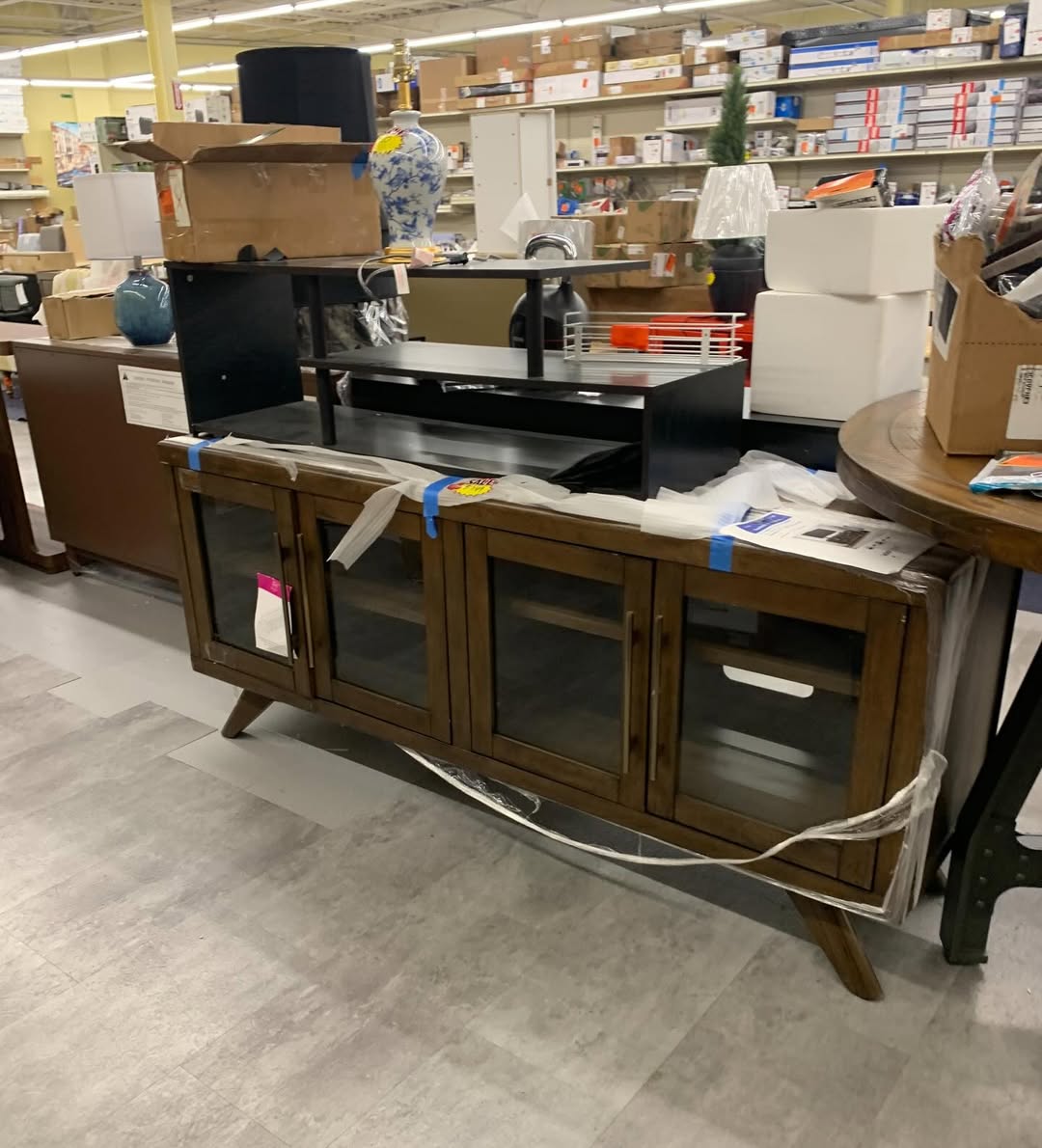 Walnut horizontal-slatted media console TV stand with glass doors on the store floor